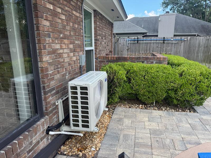 A newly installed outdoor mini-split air conditioning unit on the side of a brick house by Whitleys Heating and Air in Jacksonville, FL.