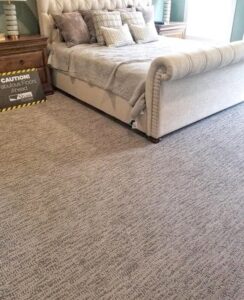 A bedroom featuring newly installed patterned gray carpet by Shop At Home Carpets in Bowling Green, KY.