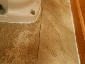 Close-up of newly installed vinyl or laminate flooring in a bathroom around a toilet by Frosty's Carpet Center, Inc. in Grand Forks, ND.