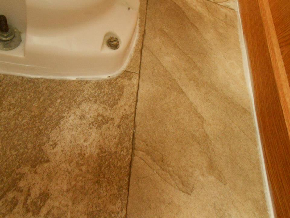 Close-up of newly installed vinyl or laminate flooring in a bathroom around a toilet by Frosty's Carpet Center, Inc. in Grand Forks, ND.