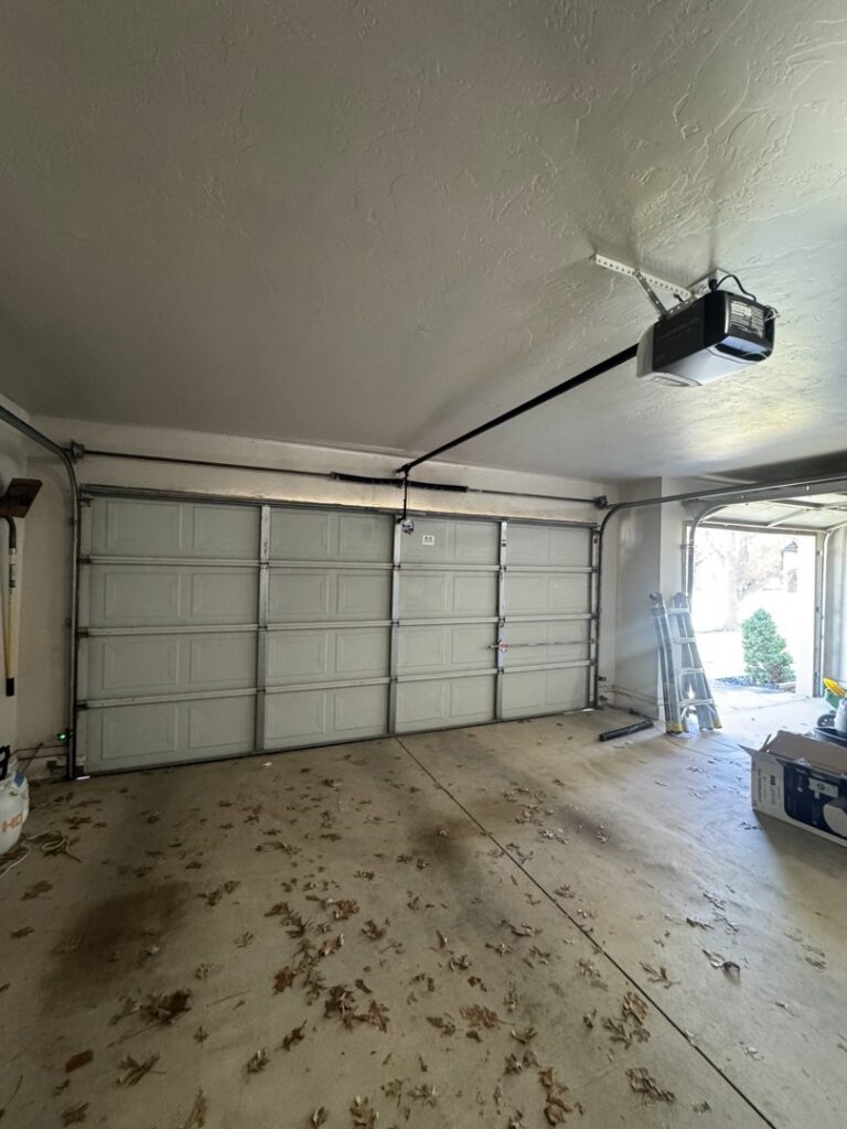 A newly installed white garage door and opener inside a garage by 405 Garage Pros in Edmond, OK.