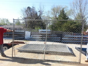 Two workers installing a chain-link fence panel for James Fencing LLC in Columbia, MO.