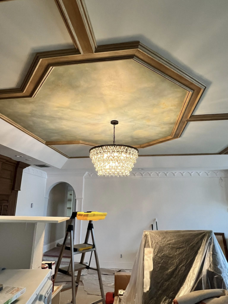 An electrician installing a beautiful crystal chandelier in a home in Tampa, FL, by ABD Electric USA.
