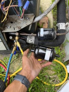 A technician installing a new refrigerant filter drier on an outdoor HVAC unit during service by Keith HVAC & Electrical Enterprises LLC in New Orleans, LA.