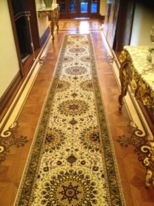 Two professionals expertly installing a patterned carpet runner on a staircase for a client of Ko-Z-Craft in Los Angeles, CA.