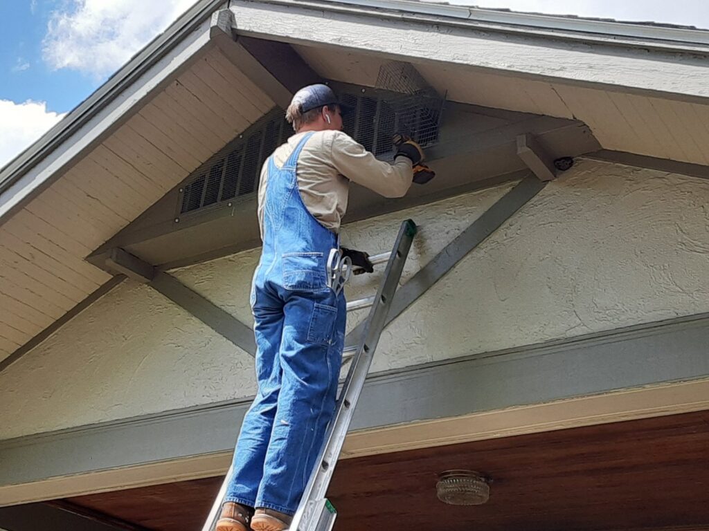 A technician from Allstate Animal Control in Elizabeth, NJ, installing protective mesh over a vent for wildlife exclusion.