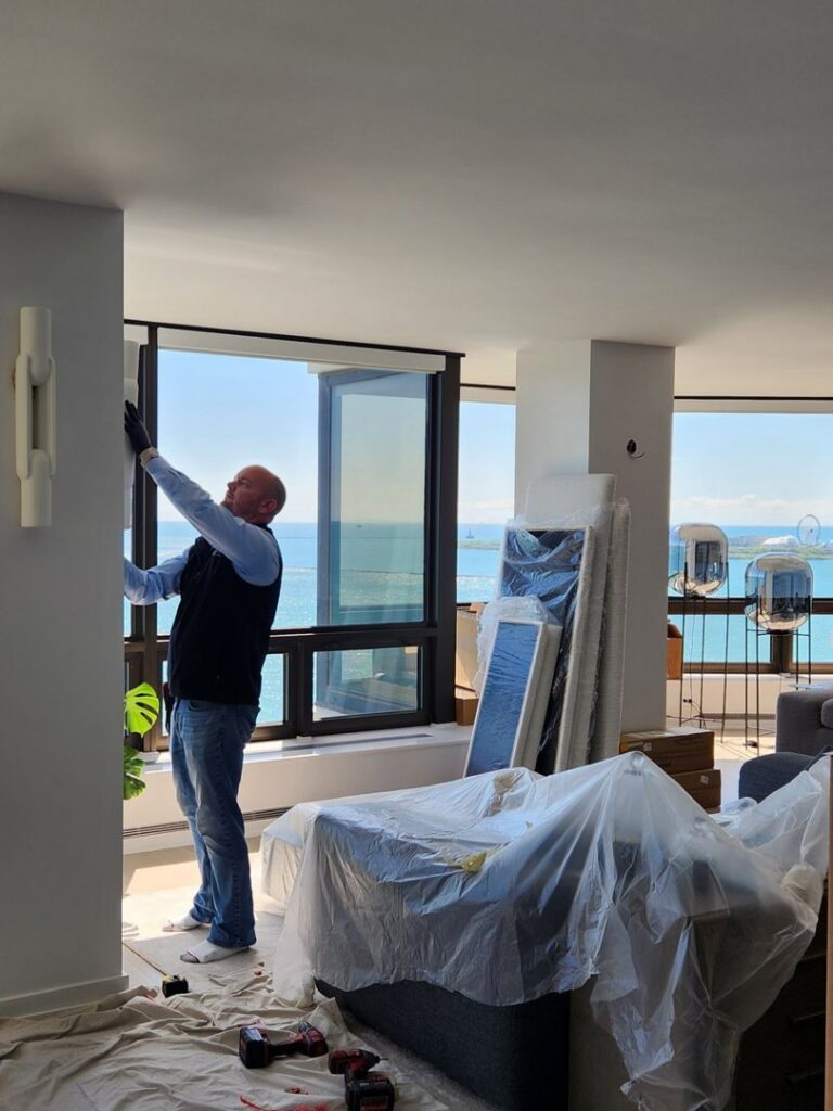 An electrician from Flavin Electric, LLC installing a modern wall light fixture in Chicago, IL