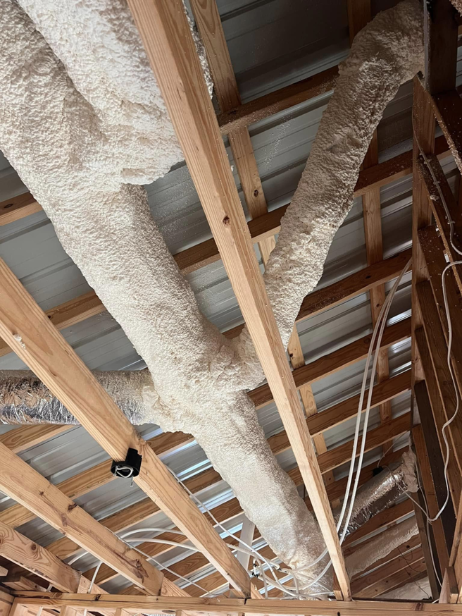 Insulated HVAC ducts installed in a ceiling with exposed wooden beams by Smartcool Inc. in Pine Bluff, AR.
