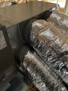 A close-up view of insulated flexible HVAC ductwork connected to a unit, installed by Jupitair in Frisco, TX.