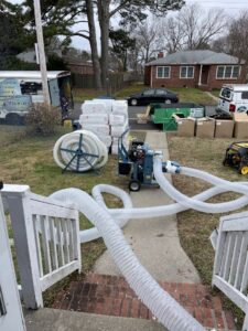 Insulation blower equipment and hoses set up outside a home for a pest control insulation job by Global Green Termite & Pest Control LLC in Hampton, VA.