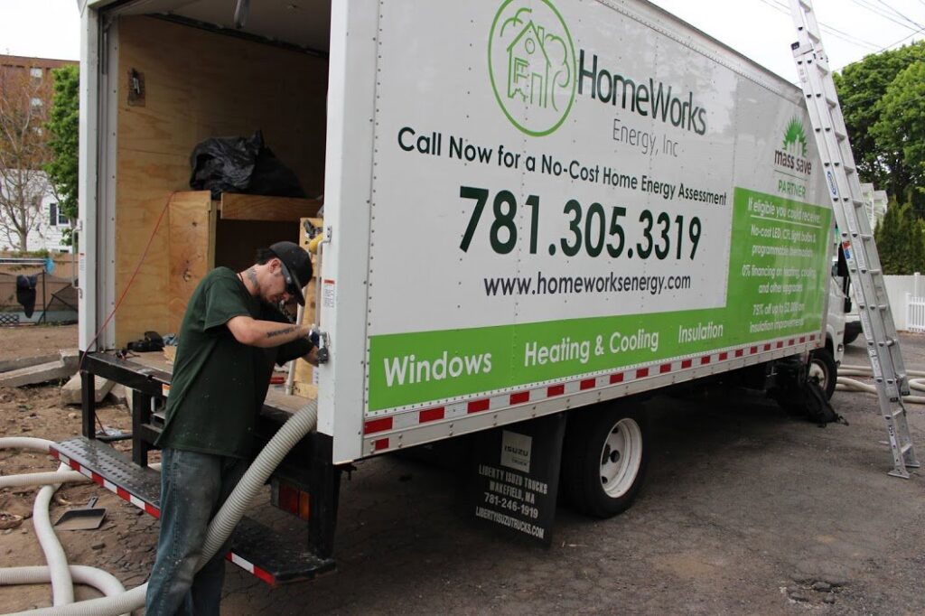 A technician performing insulation blowing service from a HomeWorks Energy truck in Medford, MA.