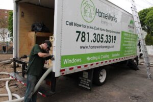 A technician performing insulation blowing service from a HomeWorks Energy truck in Medford, MA.