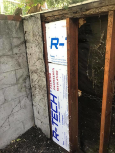 New insulation being installed in a wall cavity after a successful bee removal by Benchmark Pest Control in Bakersfield, CA.