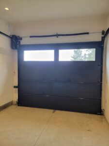 Interior view of a black garage door with windows and its operating mechanism, installed by Continental Door Company, Spokane Valley, WA.