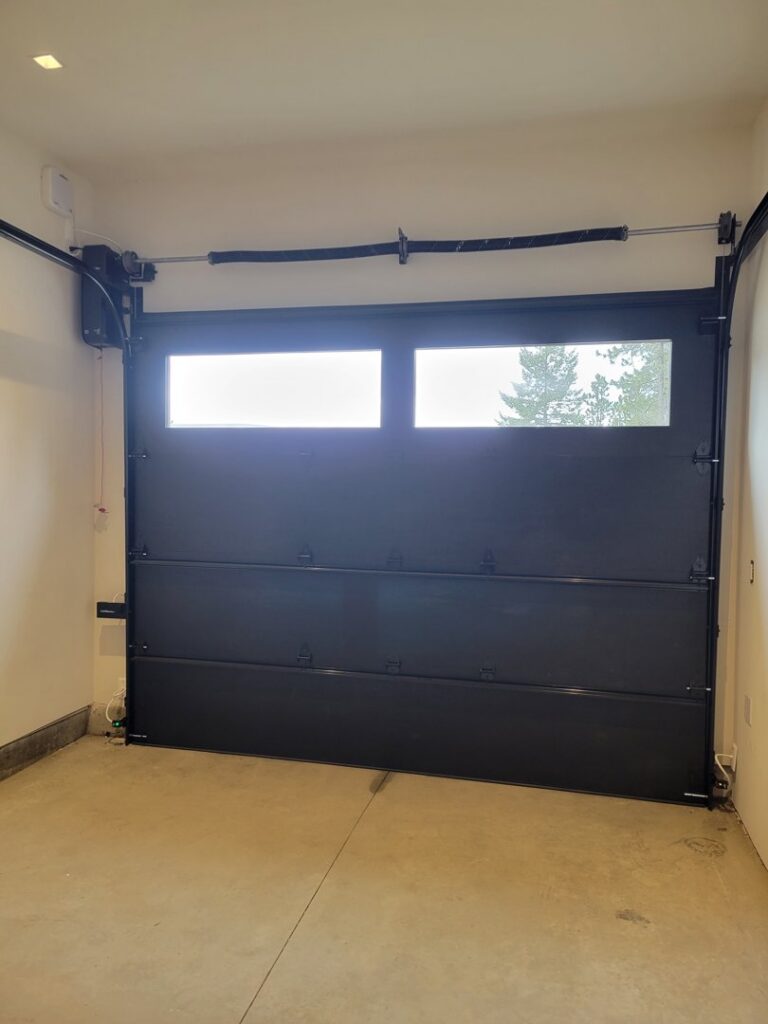 Interior view of a black garage door with windows and its operating mechanism, installed by Continental Door Company, Spokane Valley, WA.
