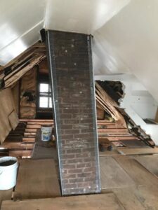 An interior brick chimney stack covered with metal mesh, indicating a chimney repair or restoration project by Colombus Chimney in Elizabeth, NJ.