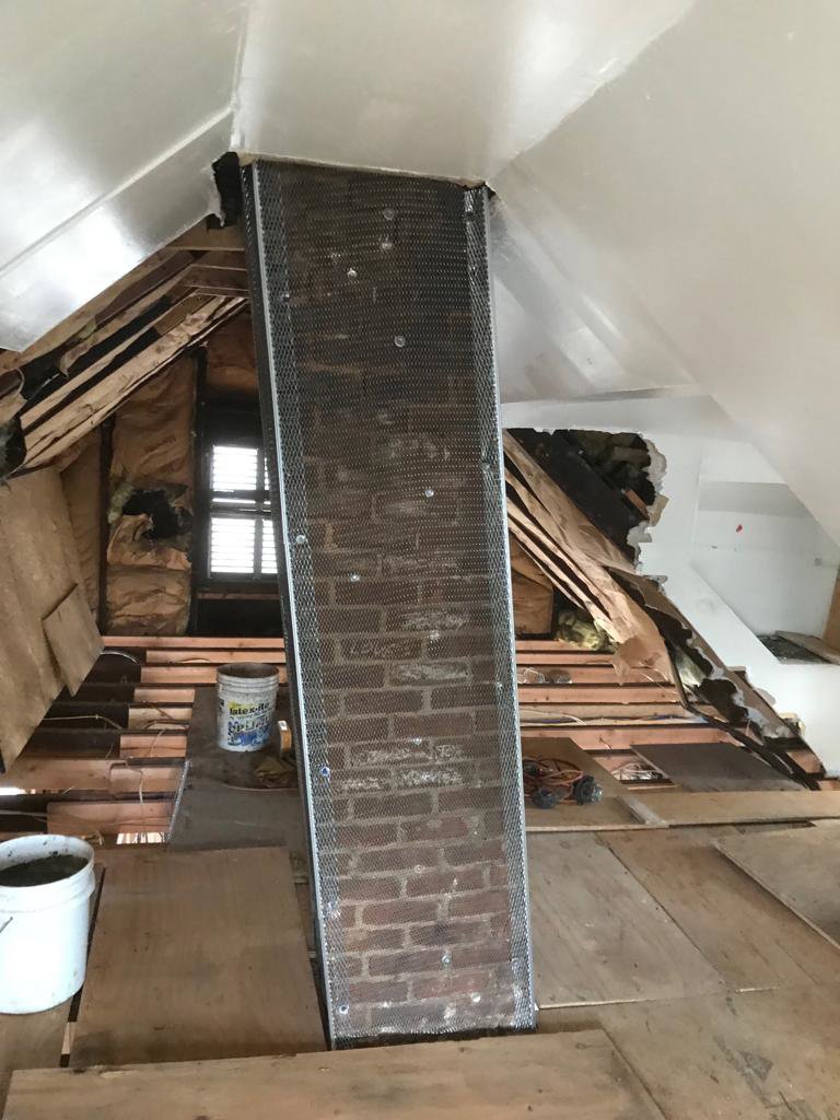 An interior brick chimney stack covered with metal mesh, indicating a chimney repair or restoration project by Colombus Chimney in Elizabeth, NJ.