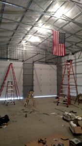 Interior view of a large commercial space with multiple garage doors installed and ladders, by Ken's Overhead Door in Clarksville, TN.