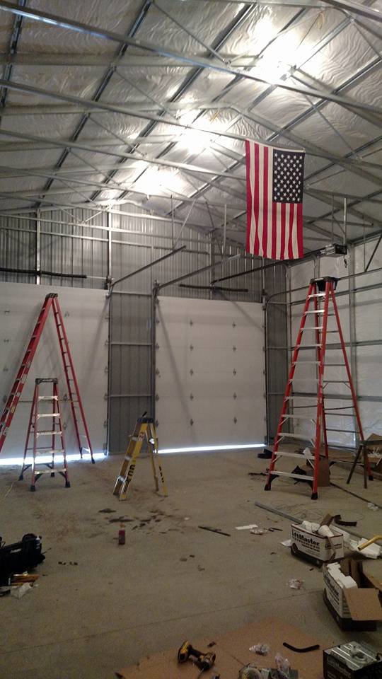 Interior view of a large commercial space with multiple garage doors installed and ladders, by Ken's Overhead Door in Clarksville, TN.