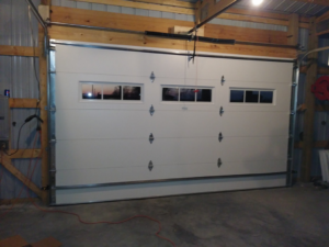 Interior view of a commercial white garage door with windows, showing the tracks and opener system, installed by R&A Overhead Door in Gower, MO.