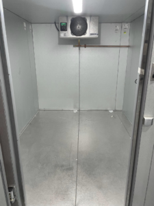 Interior view of a commercial walk-in cooler with refrigeration unit by CC Mechanical in Portland, ME.