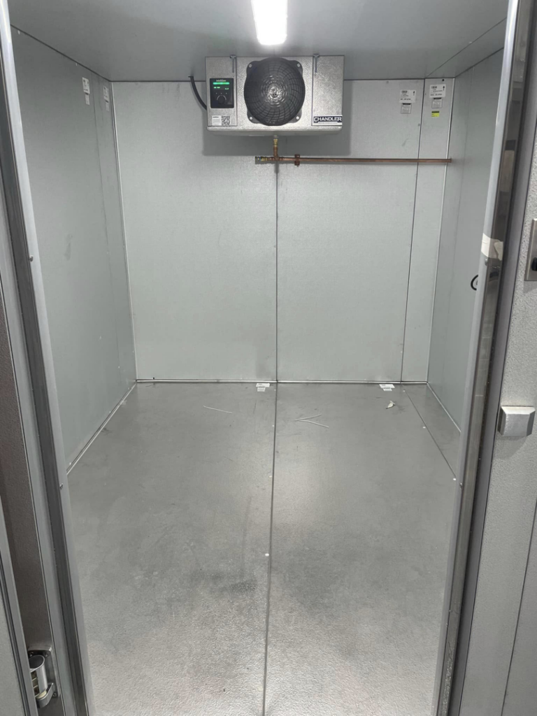 Interior view of a commercial walk-in cooler with refrigeration unit by CC Mechanical in Portland, ME.