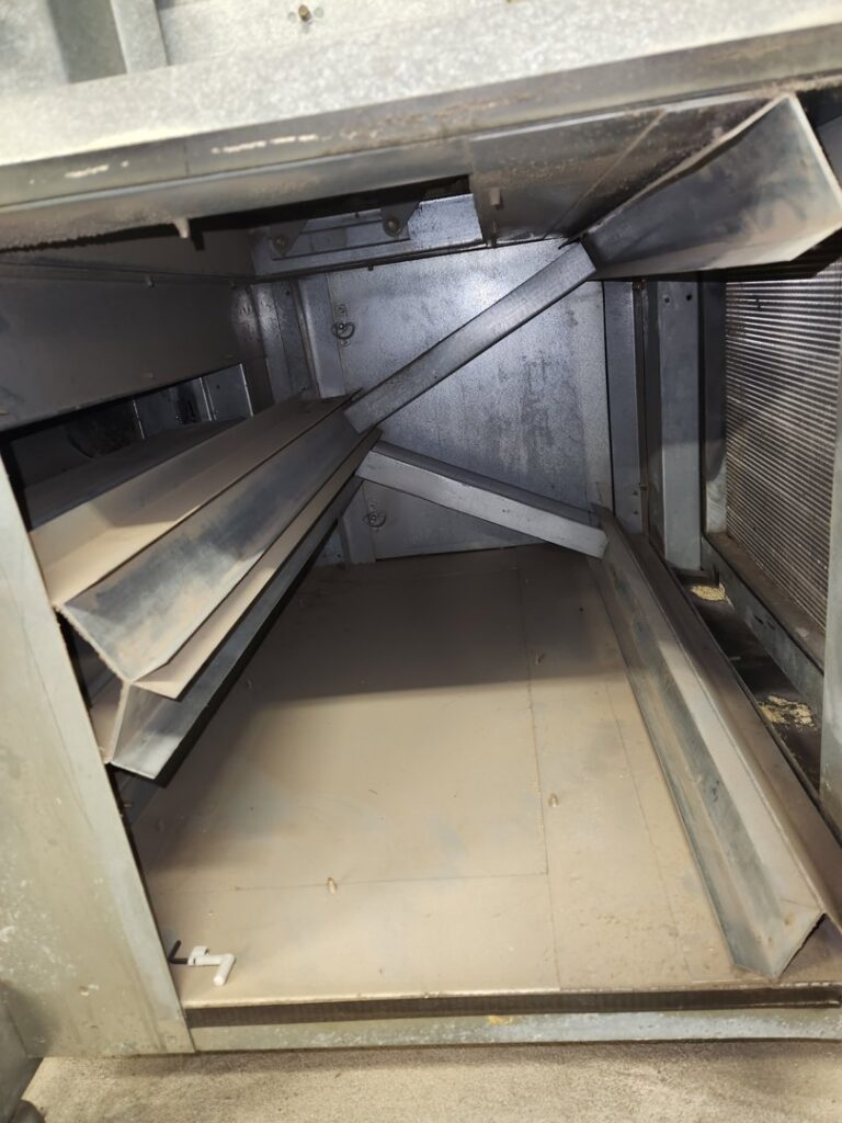 Dirty HVAC unit or large ductwork interior, showing accumulated dust and debris, ready for cleaning by DUCTZ of Siouxland in Vermillion, SD.