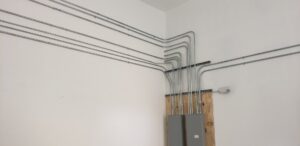 Interior electrical conduit and panels installed on a white wall by Red Earth Electric LLC in Oklahoma City, OK.