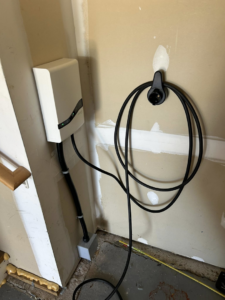 An EV charger neatly installed on an interior garage wall with conduit and wiring by MLEC in Annapolis, MD