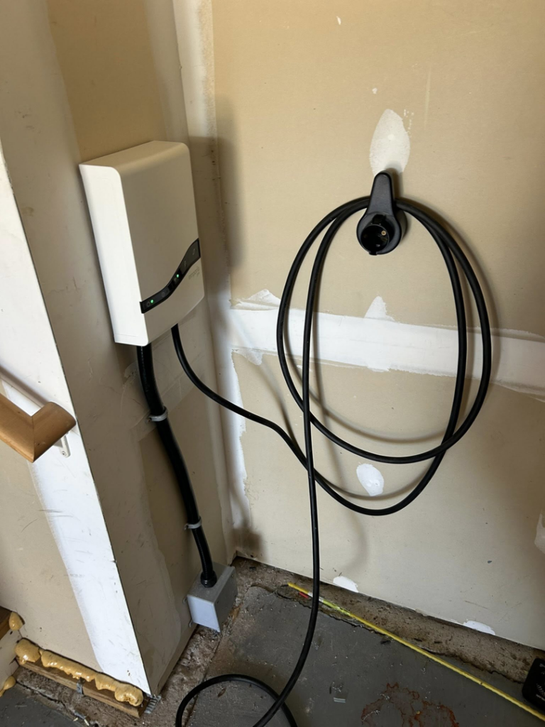 An EV charger neatly installed on an interior garage wall with conduit and wiring by MLEC in Annapolis, MD