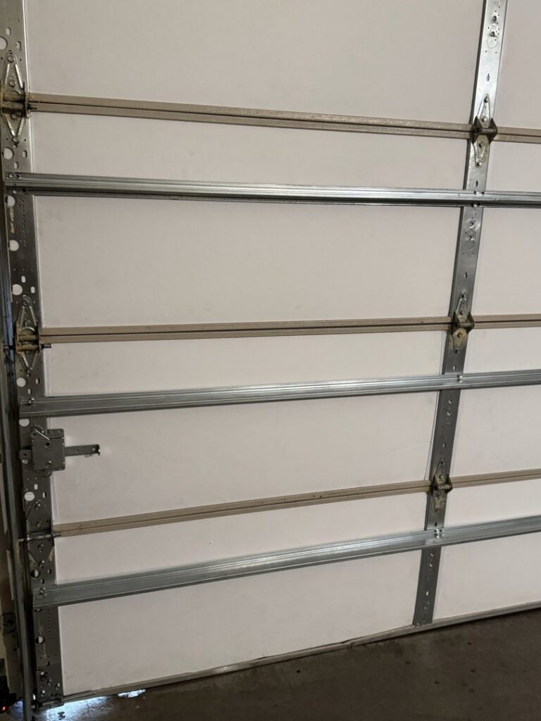 Close-up interior view of a white garage door showing hinges and support beams by 4 Sons Garage Door in Phoenix, AZ.