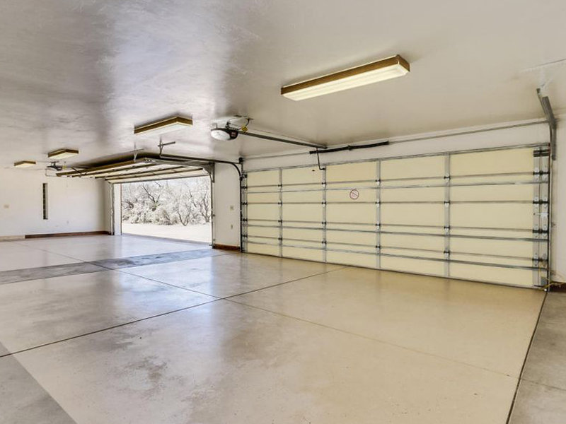 An interior view of a spacious garage showing two open garage doors with tracks and openers, installed by Johns Garage Doors in Tucson, AZ.