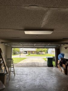 Interior view of a garage looking out, showing the open garage door and tracks by Precision Garage Door Service of Mobile in Mobile, AL.