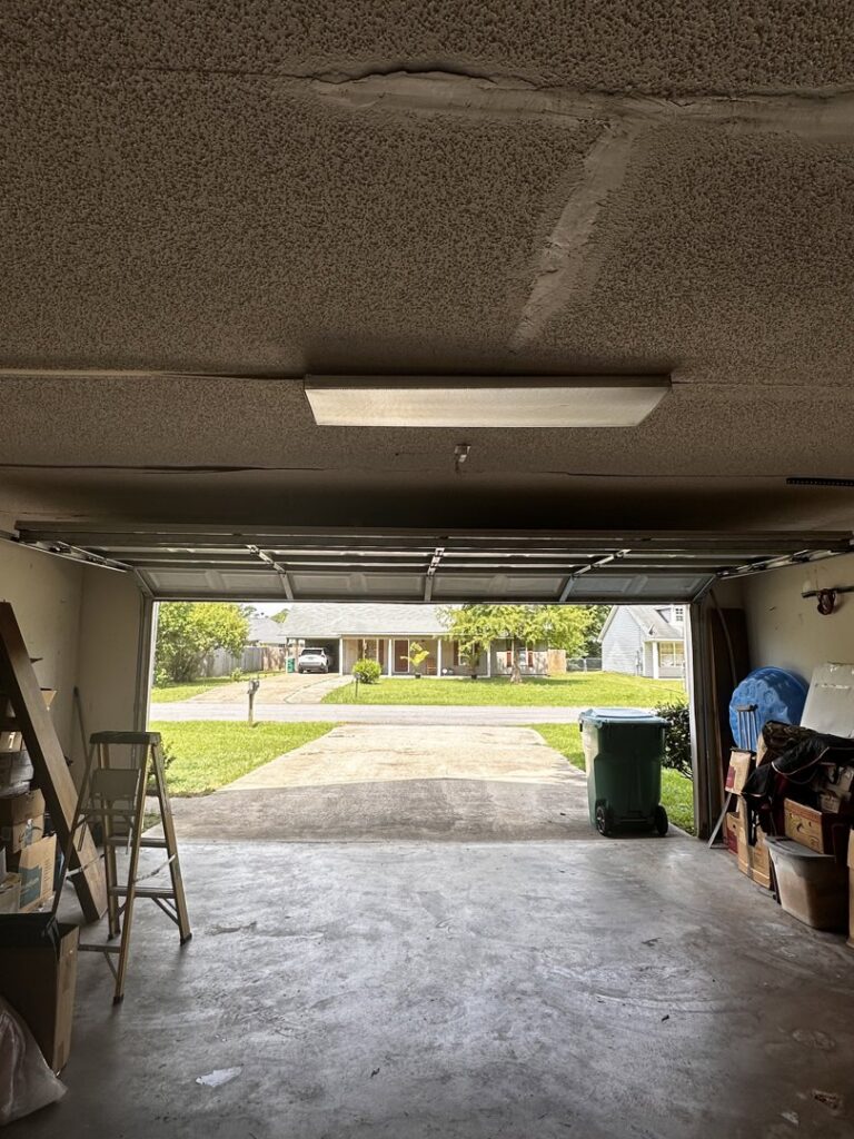 Interior view of a garage looking out, showing the open garage door and tracks by Precision Garage Door Service of Mobile in Mobile, AL.
