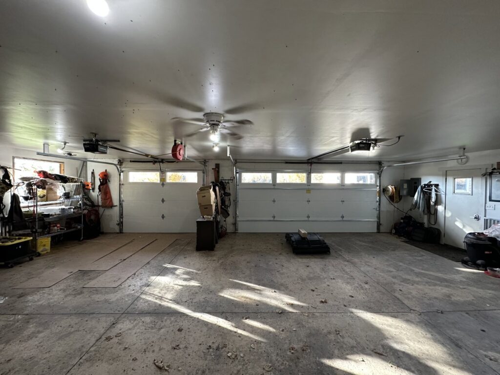An interior view of a spacious garage featuring two white garage doors and openers by AJK Door Services in Duluth, MN.