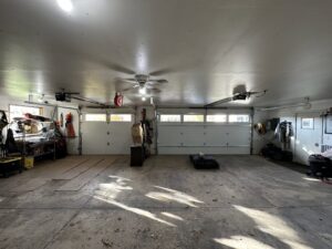 An interior view of a spacious garage featuring two white garage doors and openers by AJK Door Services in Duluth, MN.