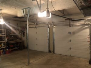 The interior of a garage showing two white garage doors with their tracks and openers, installed by Garage Doors Of Indianapolis in Indianapolis, IN