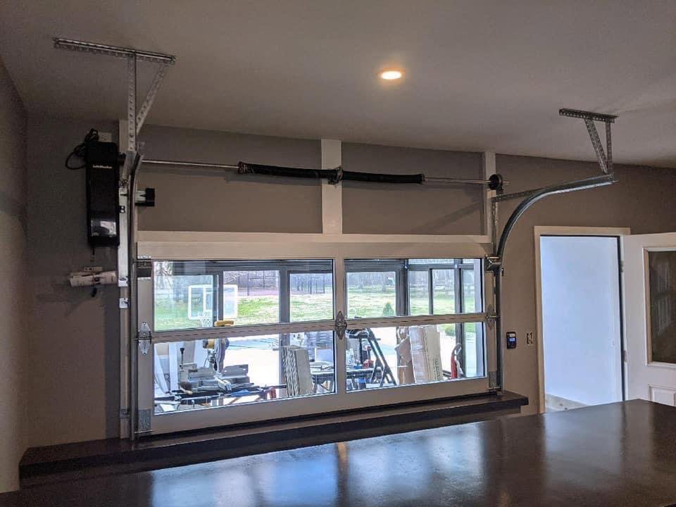 Interior view of a modern glass garage door with an opener and tracks installed by Summers Garage Door in Denver, CO.