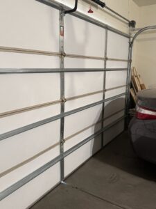 An interior side view of a white garage door showing panels, hinges, and tracks by 4 Sons Garage Door in Phoenix, AZ.