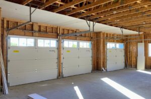 Interior view of a three-car garage with newly installed white garage doors and tracks by Superior Overhead Door, LLC in Granger, IN