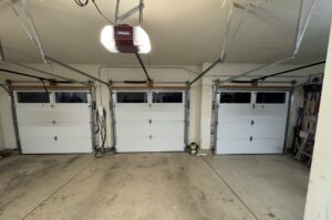 Interior view of three newly installed white garage doors and openers by Lion Heart Garage Doors in Thornton, CO.