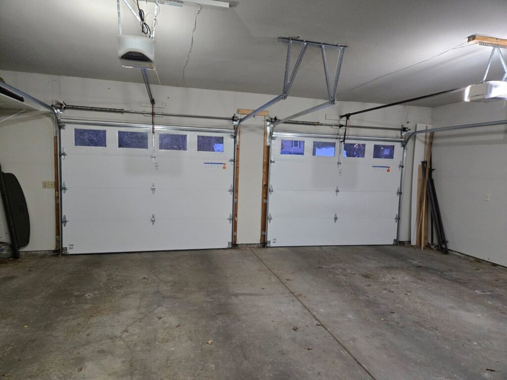 Interior view of two white garage doors with tracks and openers installed by LabraDoor Overhead Services in Eau Claire, WI.