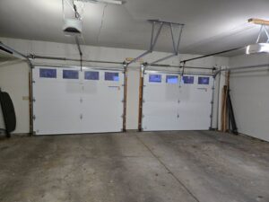 Interior view of two white garage doors with tracks and openers installed by LabraDoor Overhead Services in Eau Claire, WI.