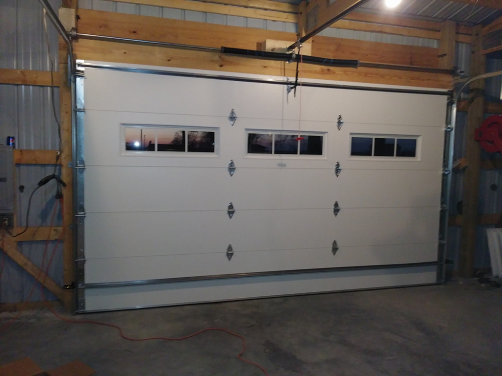 Interior view of a white commercial garage door with windows, showing the opener and tracks, installed by R&A Overhead Door in Gower, MO.