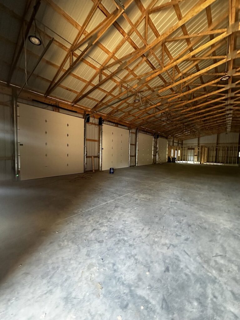 Interior view of a large commercial space with multiple white garage doors installed by Geaux Overhead Door in West Monroe, LA.