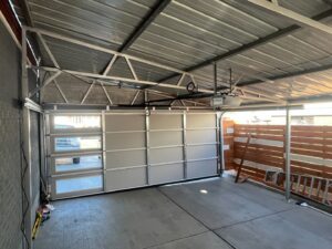 Interior view of a garage with a modern aluminum and glass garage door and opener installed by PNG Garage Doors llc in Lakewood, CO.