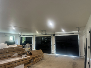 An interior view of a garage showing newly installed black garage doors and associated hardware by Reed's Garage Door Systems LLC in Sutherlin, OR.