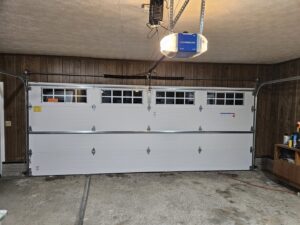 Interior view of a garage showing a newly installed white garage door with a Chamberlain opener by Steve's Overhead Door Company in Lafayette, IN.