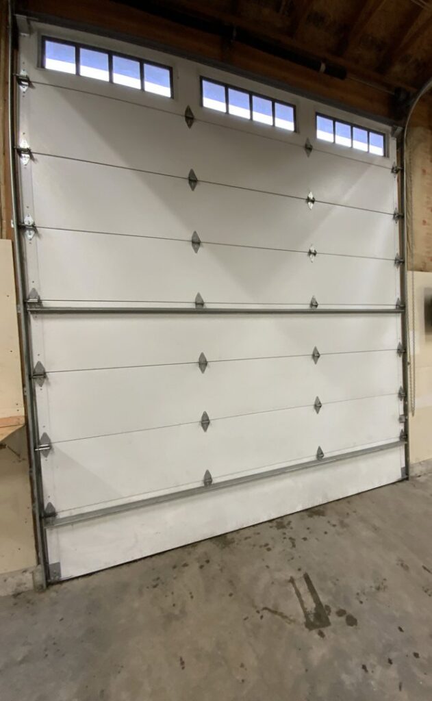 Interior view of a newly installed white garage door with windows and tracks by Steadfast Garage Door Services LLC in Federal Way, WA.