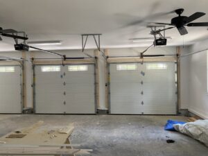 Interior view of a garage showing three newly installed white garage doors and openers by Smith's Garage Door in Clarksville, TN.